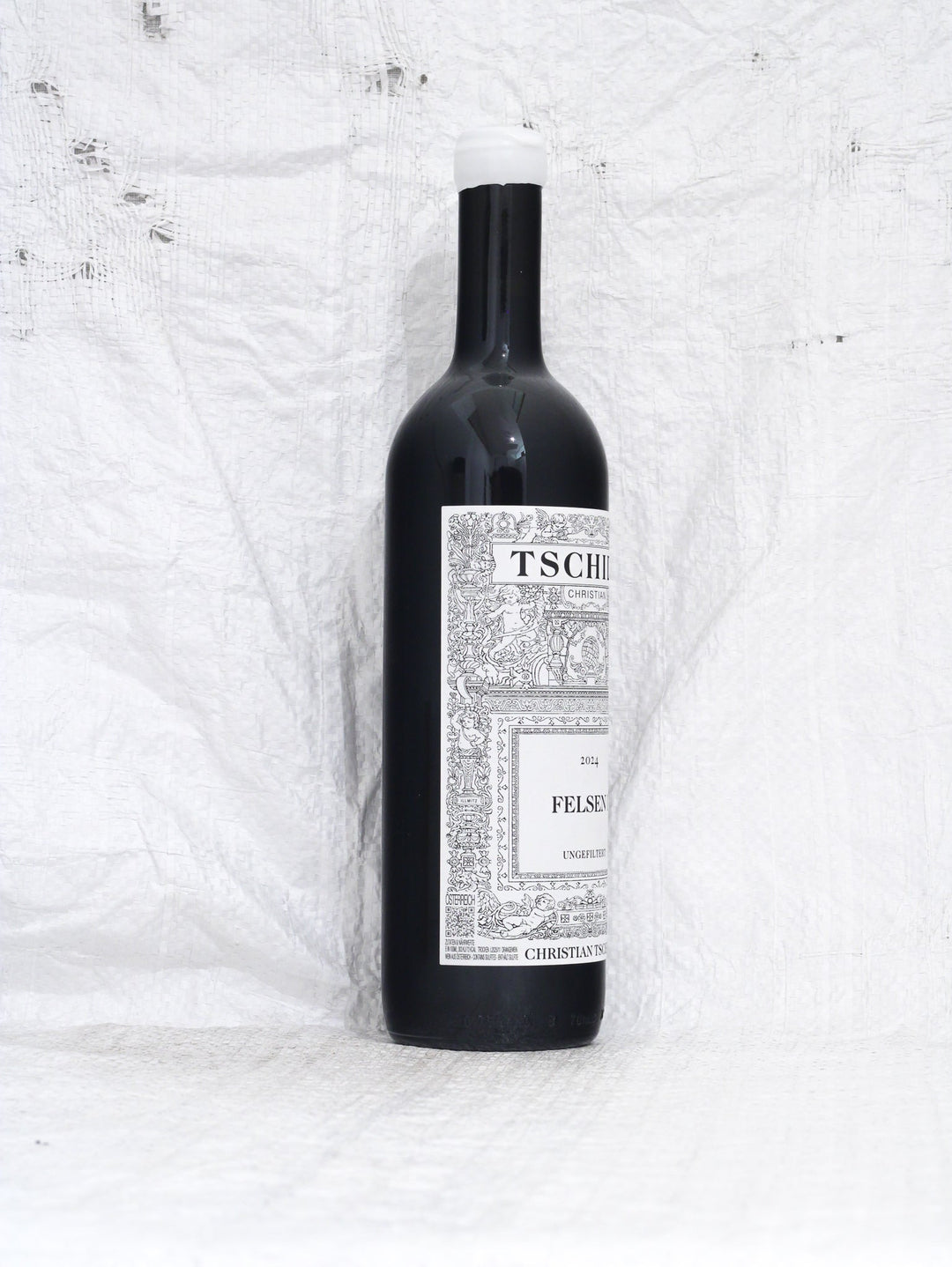 Seitenansicht Flasche Christian Tschida Felsen I 2024, ein puristischer Syrah aus dem Burgenland. Minimal Intervention Naturwein mit dem charakteristischen künstlerischen Etikett.