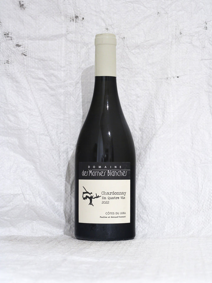Vorderansicht der Flasche Chardonnay En Quatre Vis 2022 von Domaine des Marnes Blanches, ein trockener Biowein aus dem Jura (Frankreich) mit Fokus auf Mineralität.