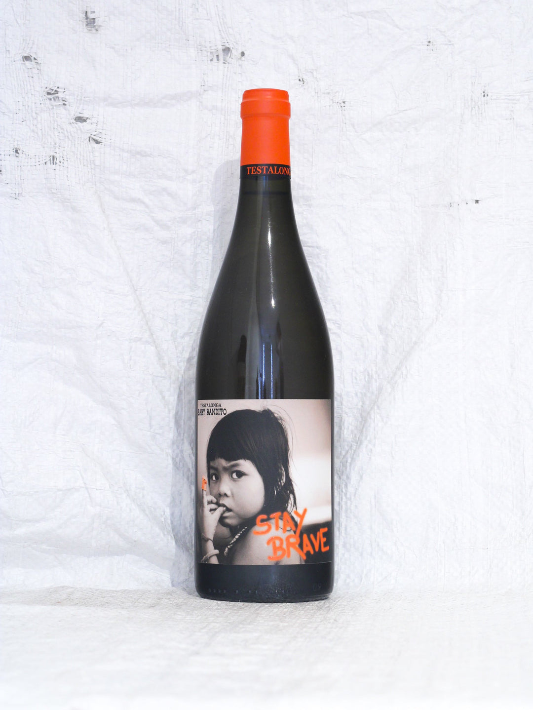 Vorderansicht der Flasche Testalonga Baby Bandito Stay Brave 2024. Ein auf der Maische vergorener Orange Wine (Chenin Blanc) aus Swartland, Südafrika. Produziert von Craig Hawkins, unfiltriert und ohne Zusätze.